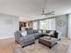 Inviting living room featuring a gray sectional sofa, ottoman, and a decorative wall clock at 4013 Ruby Run, Haines City, FL 33844