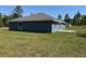Back view of a single-story home surrounded by a spacious grassy yard and natural landscapes at 4424 Sw Viola Ct, Dunnellon, FL 34431