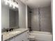 Stylish bathroom with gray tiled walls, granite countertop vanity, modern fixtures, and a shower-tub combo at 4424 Sw Viola Ct, Dunnellon, FL 34431