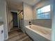 Modern bathroom with a soaking tub, tiled walls, and a window at 4424 Sw Viola Ct, Dunnellon, FL 34431
