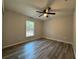 Bright bedroom featuring a ceiling fan, light gray walls, wood-look flooring, and a view at 4424 Sw Viola Ct, Dunnellon, FL 34431