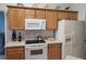 Functional kitchen with wooden cabinets, white appliances, and countertop with stove top at 4677 Nw 46Th Ave, Ocala, FL 34482