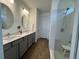 Modern bathroom with double sinks, sleek gray vanity, and glass-enclosed shower with a bench at 5785 Sw 87Th Court Rd, Ocala, FL 34481