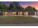 Charming brick home with red shutters, a well-manicured lawn, and a two-car garage at twilight at 6057 Se 39Th Ave, Ocala, FL 34480
