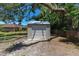 View of the backyard storage shed with metal siding and roof, surrounded by trees and greenery at 6057 Se 39Th Ave, Ocala, FL 34480