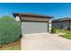 Two-car garage featuring a stone facade, modern lighting, and a paved driveway at 6132 Sw 94Th Ter, Ocala, FL 34481