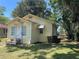 Cozy yellow cottage with white trim, steps, and a partially shaded yard at 621 Ne 20Th St, Ocala, FL 34470