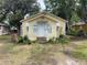 Quaint yellow bungalow with white trim, complemented by lush greenery and a welcoming front porch at 621 Ne 20Th St, Ocala, FL 34470
