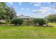 Landscaped backyard with green lawn, mature trees and manicured bushes and a screened-in patio at 6882 Sw 113Th Pl, Ocala, FL 34476