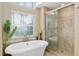 Elegant bathroom showcasing a modern soaking tub, window, and glass-enclosed shower at 6882 Sw 113Th Pl, Ocala, FL 34476