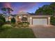 Charming single-story home with a manicured lawn, brick driveway, under a twilight sky at 6882 Sw 113Th Pl, Ocala, FL 34476
