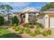 Inviting home exterior with arched windows, a double door entry, and manicured landscaping at 6882 Sw 113Th Pl, Ocala, FL 34476