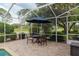 Screened-in patio features a wrought-iron table and chairs with an umbrella overlooking a clear blue pool at 6882 Sw 113Th Pl, Ocala, FL 34476