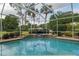 Screened-in pool and spa feature clear blue water, a stone surround and a dolphin-shaped pool cleaner at 6882 Sw 113Th Pl, Ocala, FL 34476