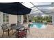Outdoor patio area features an umbrella, a dining table and chairs and overlooks a blue inground pool at 6882 Sw 113Th Pl, Ocala, FL 34476