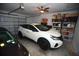 Bright garage featuring a modern white SUV, ample storage shelves, and a large roll up door at 7429 Sw 61St St, Ocala, FL 34474