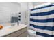 Bright bathroom with white vanity, neutral countertop and a blue and white striped shower curtain at 7571 Sw 64Th Street Rd, Ocala, FL 34474