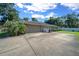 Long driveway leading to an attached garage, alongside a spacious concrete parking area and a side yard at 811 Se 49Th Ave, Ocala, FL 34471