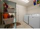 Well-lit laundry room with white washer and dryer plus shelving for ample storage space at 811 Se 49Th Ave, Ocala, FL 34471