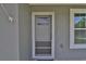 Close-up of the front door, showing a screen door, window and light gray exterior at 838 Nw 124Th Street, Citra, FL 32113