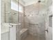Walk-in shower features a tiled surround with bench, shower head, grab bar and window at 8693 Sw 76Th Ln, Ocala, FL 34481