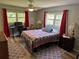 Bright bedroom featuring wood floors, large windows with red curtains, ceiling fan and a cozy quilt on the bed at 8951 Sw 202Nd Avenue Rd, Dunnellon, FL 34431