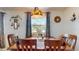 Well-lit dining room features a wooden table with place settings, complemented by charming decor and a large window at 9050 Sw 101St Ln, Ocala, FL 34481