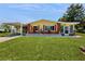 Charming yellow home features a well-manicured lawn and welcoming front porch, complemented by brick accents and a covered parking area at 9050 Sw 101St Ln, Ocala, FL 34481
