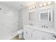 Bathroom featuring a double vanity, modern lights, and a white-tiled shower at 13505 Sw 112 Pl, Dunnellon, FL 34432