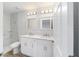 Bright bathroom with double vanity, modern lighting, and a tiled shower with glass shelf at 13505 Sw 112 Pl, Dunnellon, FL 34432