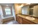 Modern bathroom features double sinks with granite countertops, vanity, a bathtub and bright vanity lighting at 15407 Sw 59Th Avenue Rd, Ocala, FL 34473