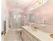 Well-lit bathroom with a large mirror, vanity, and enclosed shower and tub for efficient use of space at 17505 Se 100Th Ct, Summerfield, FL 34491