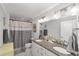Bathroom with a double sink vanity, granite counters, decorative mirrors, and a checkered shower curtain at 1781 Se 85Th Street Rd, Ocala, FL 34480