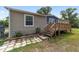 Exterior side view of a home with a deck, wooden steps, and landscaping on a lush green lawn at 1781 Se 85Th Street Rd, Ocala, FL 34480