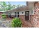 Inviting front porch with brick accents, wicker seating, and lush ferns providing a welcoming outdoor space at 1781 Se 85Th Street Rd, Ocala, FL 34480