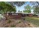 Ranch-style home with a metal roof surrounded by lush greenery and manicured landscaping at 1781 Se 85Th Street Rd, Ocala, FL 34480
