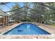 Relaxing screened-in pool featuring waterfall detail, paver deck, and plenty of room for lounging or entertaining at 1781 Se 85Th Street Rd, Ocala, FL 34480