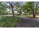 Property featuring a paved driveway leading to the house, complimented by well-manicured lawn and mature trees at 1781 Se 85Th Street Rd, Ocala, FL 34480