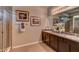 Bathroom with double vanity sinks, granite countertops, and framed floral artwork on the wall at 3080 Canopy Oak Blvd, Wildwood, FL 34785