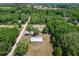 Aerial shot of a home and adjacent shop surrounded by lush greenery and scattered trees at 3112 Se 140Th Ln, Summerfield, FL 34491