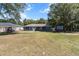 A spacious backyard with mature trees, a covered patio, and ample room for outdoor activities at 3112 Se 140Th Ln, Summerfield, FL 34491