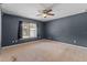 Carpeted bedroom with ceiling fan, large window, and neutral walls providing a calming retreat at 3112 Se 140Th Ln, Summerfield, FL 34491