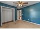 Bedroom featuring a closet and a ceiling fan with blue walls and neutral carpet at 3112 Se 140Th Ln, Summerfield, FL 34491