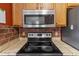 Kitchen close-up showing stainless steel microwave and cooktop alongside wooden cabinets and backsplash at 3112 Se 140Th Ln, Summerfield, FL 34491
