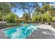 Sparkling pool with basketball hoop and lounge chairs surrounded by lush, mature landscaping and secure fencing at 400 Se 45Th Ter, Ocala, FL 34471