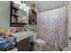 Well-lit bathroom with a sleek vanity, decorative shelves, and a shower with a floral curtain at 408 Etheredge St, Bushnell, FL 33513