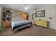 Bedroom featuring carpet floors, ceiling fan, floral wallpaper accent wall, and a large dresser at 408 Etheredge St, Bushnell, FL 33513