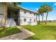 Charming two-story condo featuring lush landscaping with palm trees and a sidewalk leading to the entrance at 450 Fairways Cir # A101, Ocala, FL 34472
