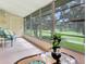 A cozy sunroom with a chair, coffee table and view of the green golf course at 700 Midway Dr # B, Ocala, FL 34472