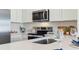 Kitchen with stainless steel appliances, white cabinets, quartz countertops, and glassware accents at 8413 Gower Trl, Wildwood, FL 34785